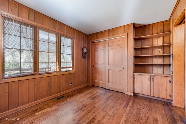 unfurnished bedroom with wood walls, a closet, and wood-type flooring