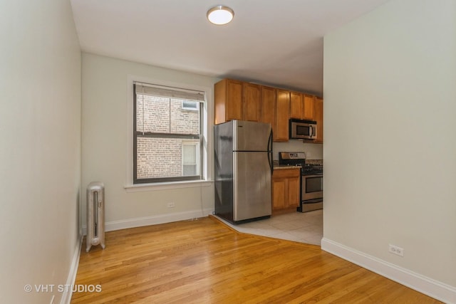 kitchen featuring appliances with stainless steel finishes, radiator, and light wood-type flooring