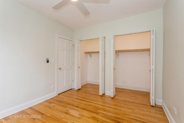 unfurnished bedroom with ceiling fan, multiple closets, and hardwood / wood-style floors