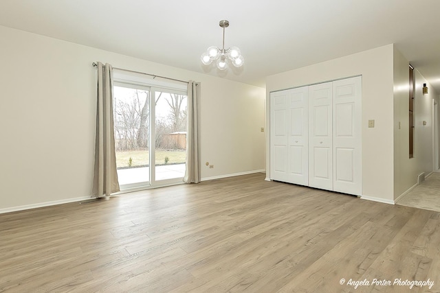 unfurnished bedroom with access to exterior, a closet, a chandelier, and light hardwood / wood-style flooring