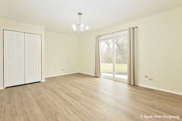 unfurnished bedroom with light wood-type flooring, a closet, a chandelier, and access to outside