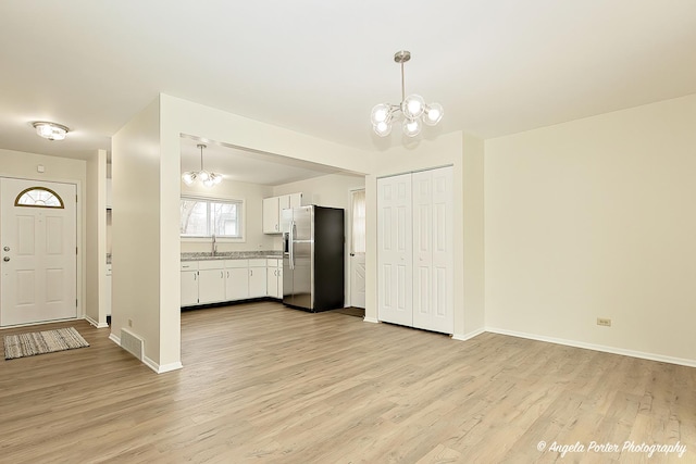 kitchen with decorative light fixtures, white cabinets, stainless steel fridge, and an inviting chandelier