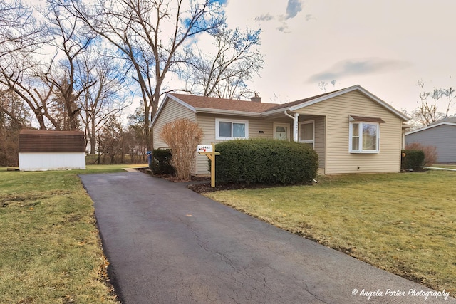 view of front of house featuring a front lawn and a storage shed