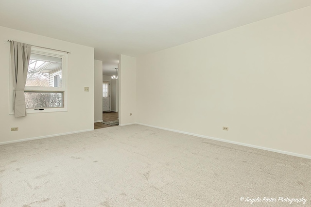 carpeted empty room featuring a notable chandelier