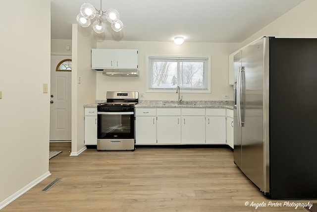 kitchen featuring appliances with stainless steel finishes, light wood-type flooring, a chandelier, white cabinets, and sink