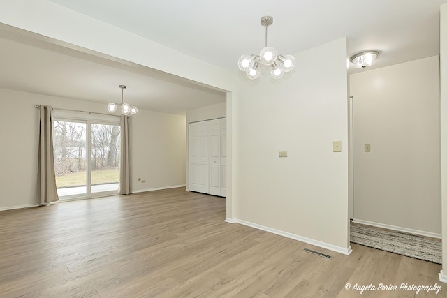 empty room with light hardwood / wood-style flooring and a chandelier