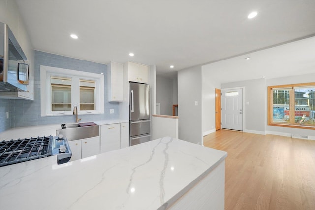 kitchen with white cabinetry, stainless steel appliances, and tasteful backsplash