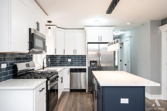 kitchen featuring a kitchen island, white cabinetry, hanging light fixtures, appliances with stainless steel finishes, and dark hardwood / wood-style flooring