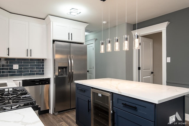 kitchen with pendant lighting, white cabinets, appliances with stainless steel finishes, wine cooler, and decorative backsplash