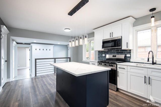 kitchen featuring a center island, decorative light fixtures, white cabinetry, stainless steel appliances, and sink