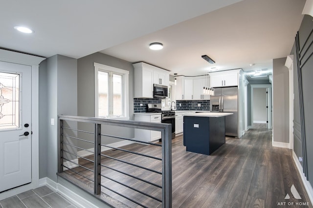 kitchen with tasteful backsplash, a kitchen island, appliances with stainless steel finishes, dark wood-type flooring, and white cabinets