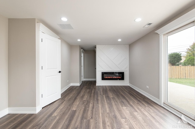 unfurnished living room with a large fireplace and dark hardwood / wood-style floors