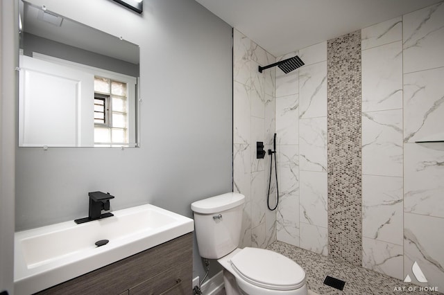 bathroom featuring toilet, tiled shower, and vanity