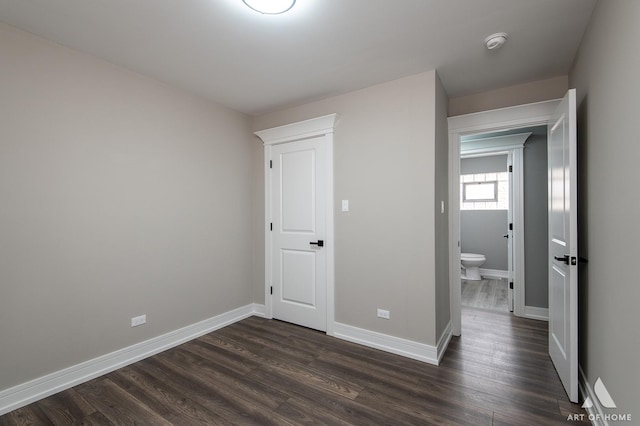 unfurnished bedroom with ensuite bath and dark hardwood / wood-style flooring