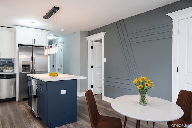 kitchen featuring a center island, white cabinetry, hanging light fixtures, appliances with stainless steel finishes, and dark hardwood / wood-style flooring