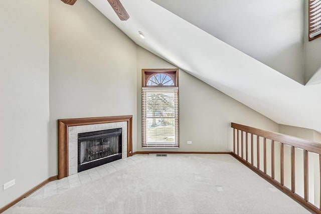 interior space with a tiled fireplace, lofted ceiling, and light carpet