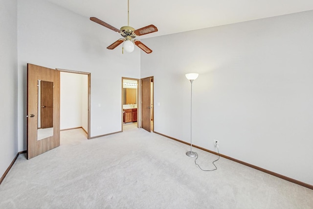 unfurnished bedroom with ceiling fan, ensuite bathroom, high vaulted ceiling, and carpet