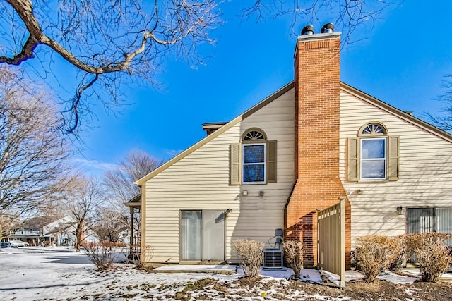 snow covered rear of property with central AC unit