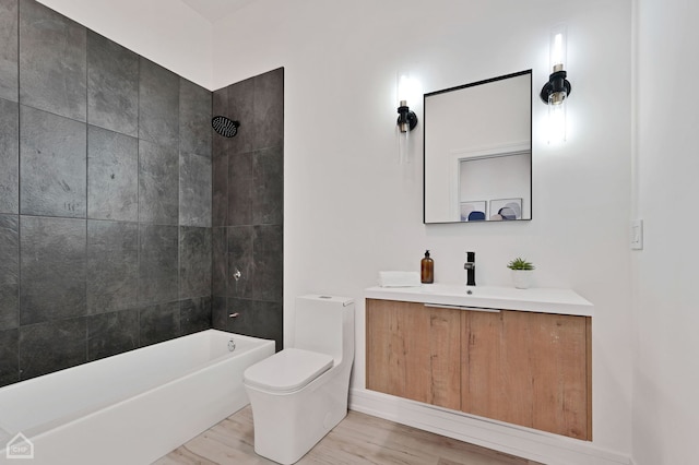 full bathroom with toilet, tiled shower / bath, hardwood / wood-style floors, and vanity