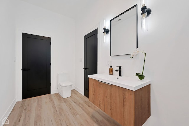 bathroom with toilet, vanity, and hardwood / wood-style floors