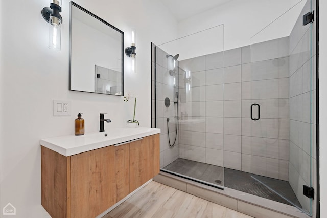 bathroom with walk in shower, vanity, and wood-type flooring