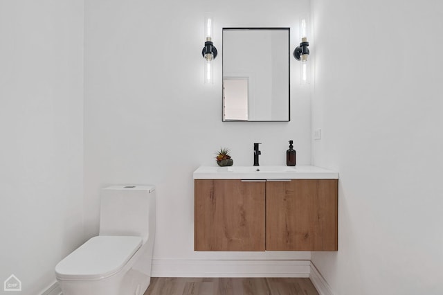 bathroom with toilet, vanity, and hardwood / wood-style floors