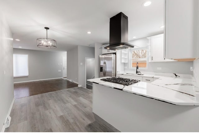 kitchen featuring pendant lighting, sink, island exhaust hood, stainless steel appliances, and white cabinets