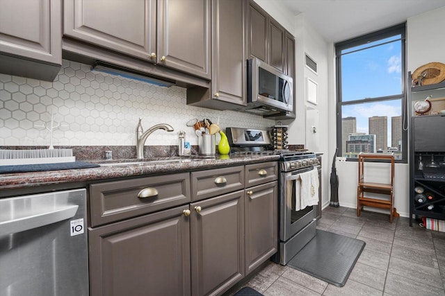 kitchen featuring light tile patterned flooring, appliances with stainless steel finishes, tasteful backsplash, sink, and floor to ceiling windows