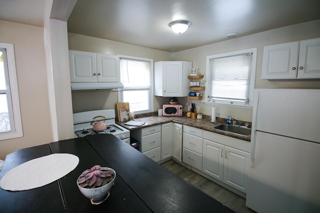 kitchen with white cabinetry, sink, white appliances, and hardwood / wood-style flooring