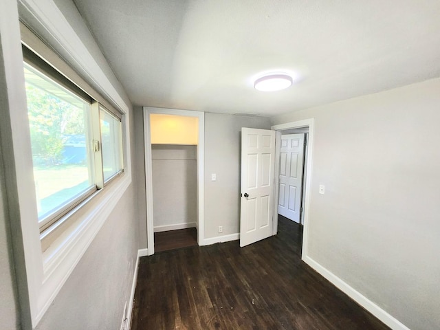 unfurnished bedroom featuring a closet, a walk in closet, and dark hardwood / wood-style floors