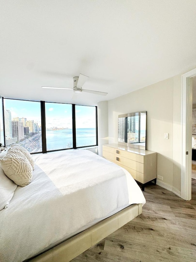 bedroom with ceiling fan, multiple windows, and light hardwood / wood-style floors