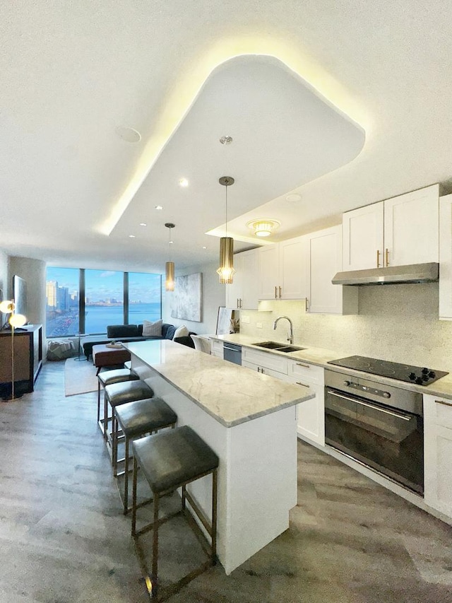 kitchen featuring a center island, hanging light fixtures, black appliances, white cabinets, and sink