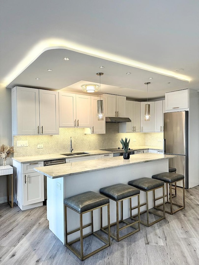 kitchen featuring pendant lighting, sink, light hardwood / wood-style flooring, white cabinets, and stainless steel fridge