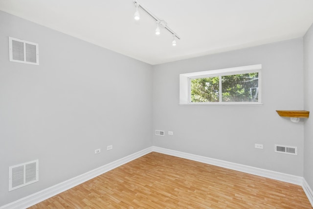 unfurnished room with track lighting and hardwood / wood-style flooring