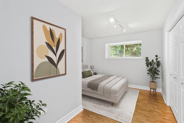 bedroom with a closet, track lighting, and hardwood / wood-style flooring