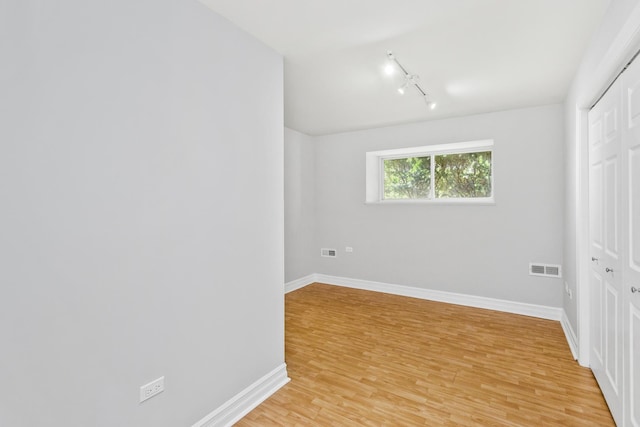 unfurnished bedroom featuring a closet, track lighting, and light hardwood / wood-style flooring