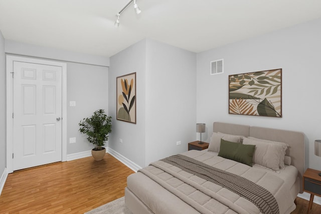 bedroom with track lighting and wood-type flooring