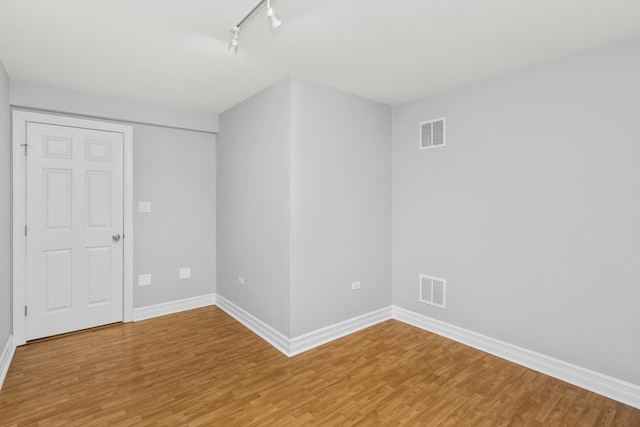 spare room with rail lighting and hardwood / wood-style flooring