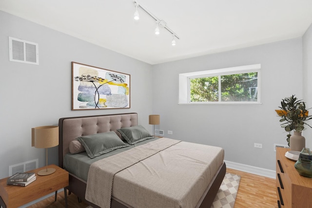 bedroom featuring rail lighting and light hardwood / wood-style flooring