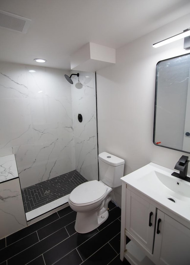 bathroom featuring toilet, vanity, and a tile shower