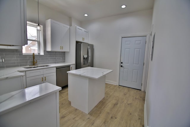 kitchen featuring pendant lighting, a kitchen island, sink, white cabinetry, and stainless steel appliances