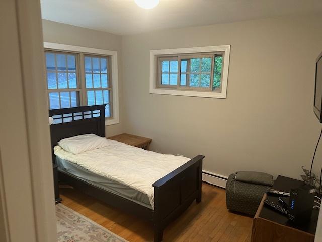 bedroom with hardwood / wood-style flooring and baseboard heating