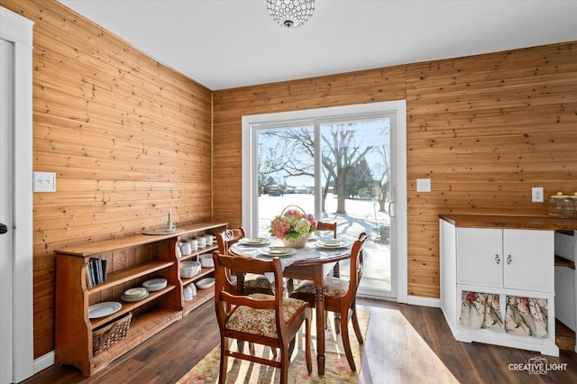 dining area with dark hardwood / wood-style floors and wood walls