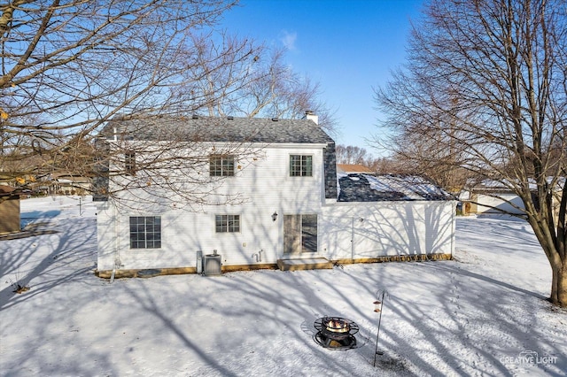 snow covered rear of property featuring an outdoor fire pit and central AC unit