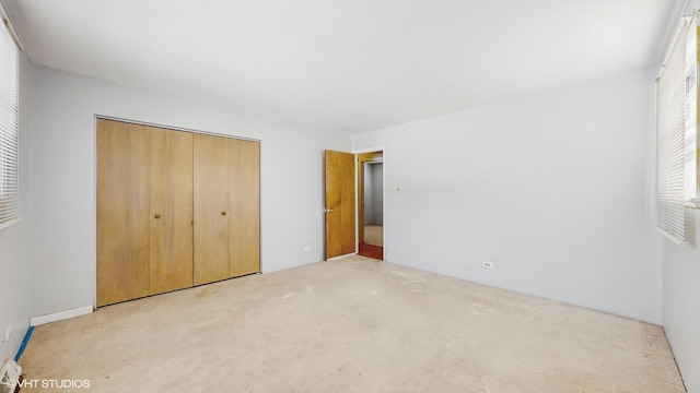 unfurnished bedroom featuring light carpet and a closet