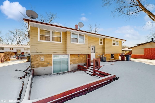 snow covered back of property featuring cooling unit