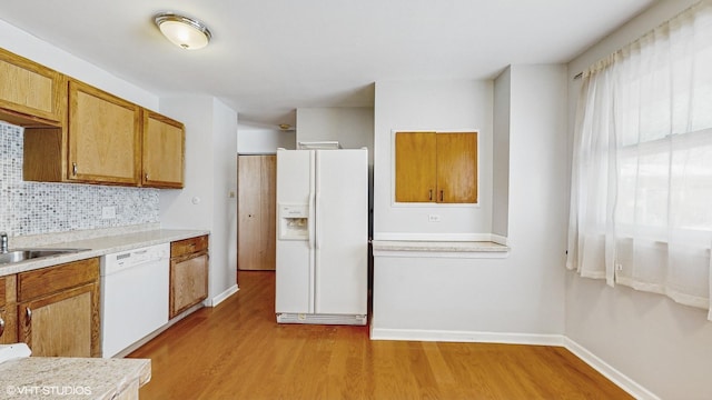 kitchen with backsplash, sink, white appliances, and light hardwood / wood-style floors