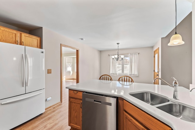 kitchen featuring decorative light fixtures, dishwasher, sink, white refrigerator, and light hardwood / wood-style flooring