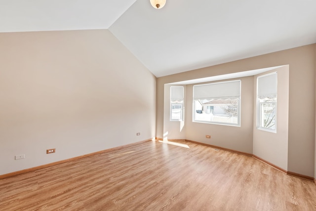 spare room featuring lofted ceiling and light hardwood / wood-style floors