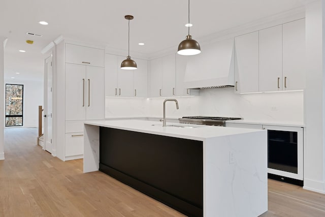 kitchen with light hardwood / wood-style floors, pendant lighting, sink, white cabinetry, and custom range hood